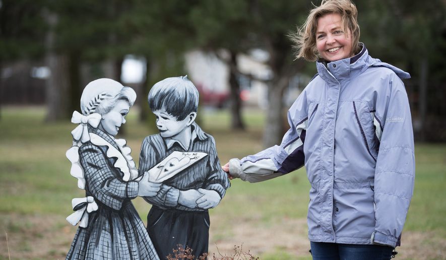 In this April 24, 2018, photo, Marah Sandoz stands next to "Jane and John" on the northeast corner of the city park in Taylor, Neb. Sandoz paints plywood cutouts of people she calls the "Taylor Villagers" for display around the town in an effort to attract tourists. (Rebecca Gratz/Omaha World-Herald via AP)