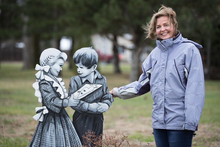 In this April 24, 2018, photo, Marah Sandoz stands next to "Jane and John" on the northeast corner of the city park in Taylor, Neb. Sandoz paints plywood cutouts of people she calls the "Taylor Villagers" for display around the town in an effort to attract tourists. (Rebecca Gratz/Omaha World-Herald via AP)