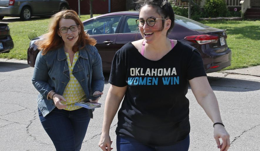 Chelsea Abney, right, walks with Danielle Ezell, Democratic state senate candidate, as they knock on doors in The Village, Okla., Saturday, May 12, 2018. Abney grew up surrounded by red. She was a reliable Republican herself until 2015, when she took an online quiz during the party's crowded presidential primary to see which candidate she should vote for. The quiz told her she was a Hillary Clinton voter. (AP Photo/Sue Ogrocki)