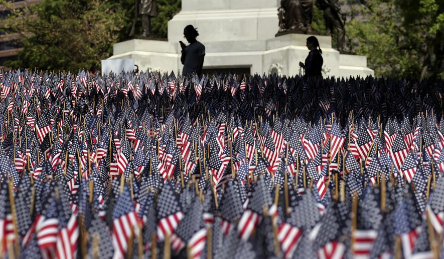 In this May 24, 2018, photo, people view flags on Boston Common in Boston, which are placed there for Memorial Day. The solemn display of tens of thousands of U.S. flags that first appeared on Boston Common a decade ago to honor service members who have died defending the nation is slowly becoming a national movement. The flag gardens, as they are known, can be seen this weekend in Texas, Louisiana, Ohio and New York. (AP Photo/Elise Amendola)