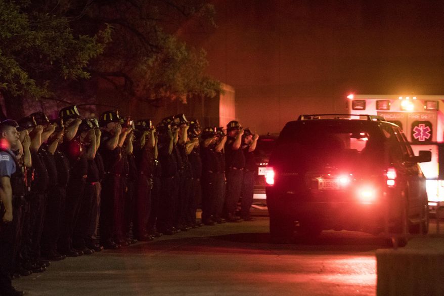 Chicago Fire Department and Chicago Police personnel salute as a procession of emergency vehicles including the ambulance carrying the body of Chicago fire department diver Juan Bucio travels to the Cook County medical examiner's office Tuesday, May 29, 2018 in Chicago. Bucio, 46, died while searching for a man who fell off a boat on the Chicago River, early Tuesday. (Ashlee Rezin/Sun Times via AP)