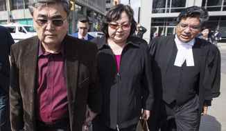 File - In this April 11, 2017 file photo, Akhmet Tokbergenov, left, and Dinara Tokbergenova, parents of alleged Yahoo hacker Karim Baratov, leave the court after their son was denied bail, with lawyer Deepak Paradkar, right, in Hamilton, Ont. A Canadian computer hacker was sentenced to five years in prison in connection with a massive security breach at Yahoo that federal agents say was directed by Russian government spies. U.S. Judge Vince Chhabria also on Tuesday, May 29, 2018, fined Karim Baratov $250,000. (Mark Blinch/The Canadian Press via AP, File)