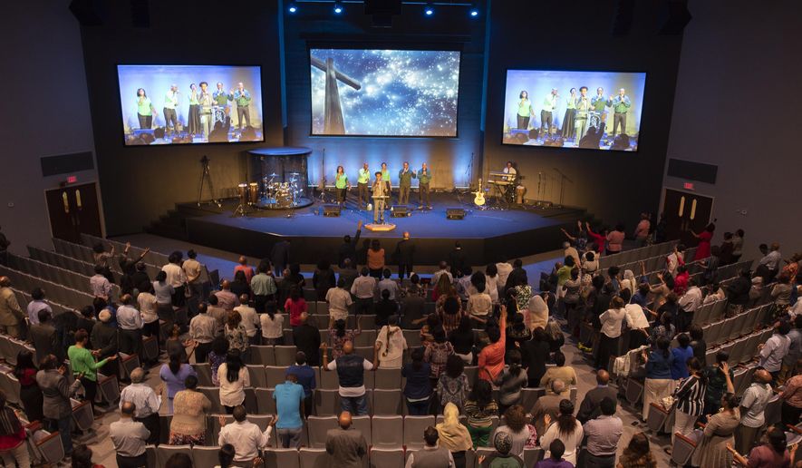 In a Sunday, May 20, 2018 photo, the congregation prays during the musical portion of services at the Ethiopian Evangelical Baptist Church in Garland, Texas. The church was founded around 1983 after a few Dallas-area residents from Ethiopia began to have services at a park. It recently moved into the former Orchard Hills Baptist Church building. (Rex C. Curry/The Dallas Morning News via AP)