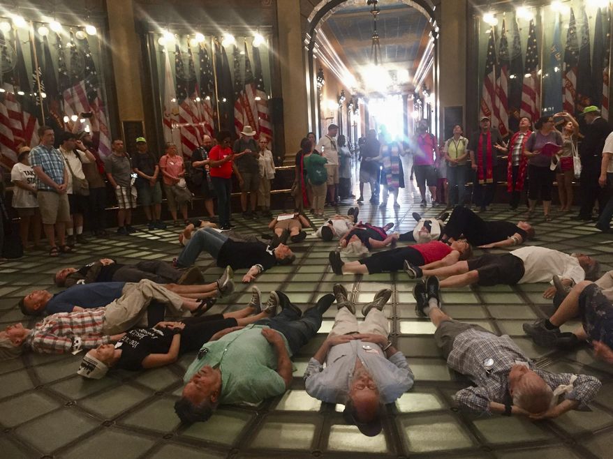 Protesters for the Michigan Poor People's Campaign lie down on the rotunda of the Michigan capitol Tuesday, May 29, 2018 in Lansing, Mich., as part of a die-in to protest war and militarism. Nineteen were arrested and received trespassing citations for not leaving when ordered. (AP Photo/Alice Yin)