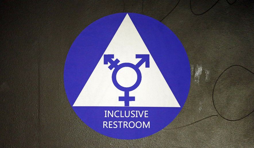 FILE - In this May 17, 2016, file photo, a new sticker designates a gender neutral bathroom at Nathan Hale high school in Seattle. On college campuses and in workplaces, across social media and in deference to nonbinary people, gender-neutral pronouns are more than just a new wave of political correctness. Pronouns “they” and “them” seem to be winning the race of acceptance as gender neutrals. (AP Photo/Elaine Thompson, File)
