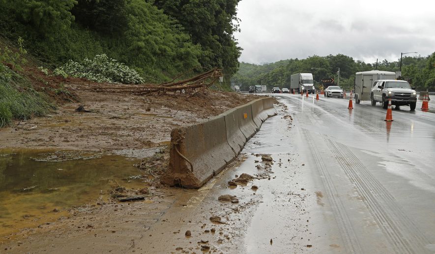 Drivers move past blocked off lanes of I-40 near Old Fort, N.C., Wednesday, May 30, 2018 after heavy rains from the fringes of Subtropical Storm Alberto caused a mudslide Tuesday evening. A tree that fell on a power line in Old Fort, North Carolina, caused a 250-acre wildfire Wednesday, leading to temporary evacuations and damage to some structures. (AP Photo/Chuck Burton)