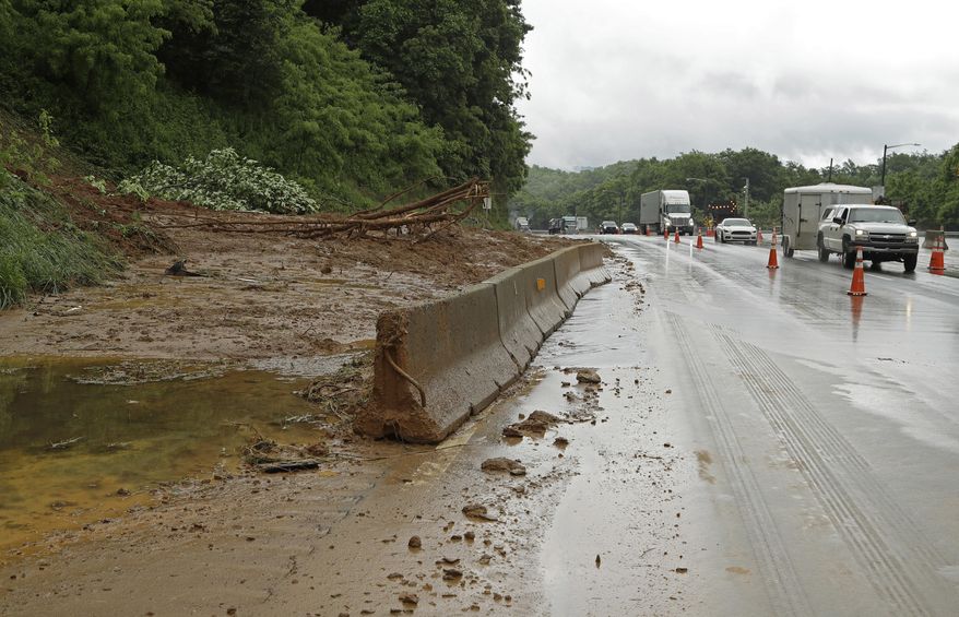 Drivers move past blocked off lanes of I-40 near Old Fort, N.C., Wednesday, May 30, 2018 after heavy rains from the fringes of Subtropical Storm Alberto caused a mudslide Tuesday evening. A tree that fell on a power line in Old Fort, North Carolina, caused a 250-acre wildfire Wednesday, leading to temporary evacuations and damage to some structures. (AP Photo/Chuck Burton)