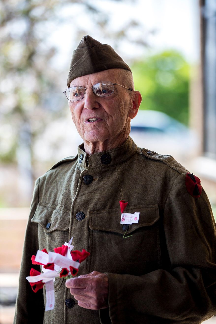 ADVANCE FOR USE SATURDAY, JUNE 2 - In this May 18, 2018 photo, Ervin Shudarek, 88, wears his father's World War I uniform as he hands out small, handmade poppies made of tissue paper for National Poppy Day at the Copps grocery store in Plover< Wis. (Alexandra Wimley/The Wausau Daily Herald via AP)