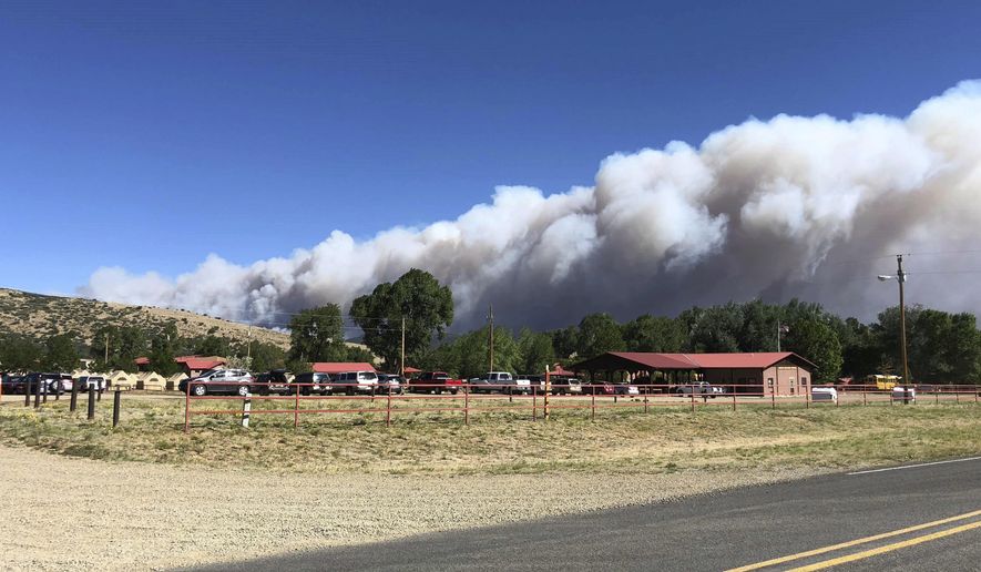 A plume of smoke from a wildfire rises behind Philmont Scout Ranch, Friday, June 1, 2018, near Cimarron, N.M. A wildfire raced across a swath of tinder-dry forest in northeastern New Mexico on Friday, sending up a thick plume of smoke that forced residents to flee their homes as heat and wind threatened to drive the flames. (Marty Mayfield/KRTN Radio via AP)