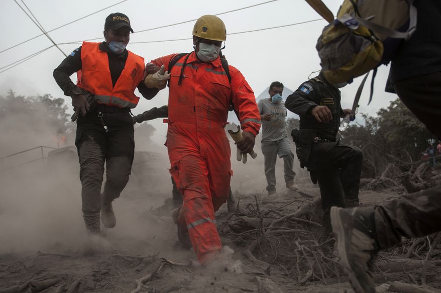 Firefighters and police are forced to evacuate a search and rescue effort as the Volcan de Fuego, or "Volcano of Fire," continues to spill out smoke and ash in Escuintla, Guatemala, Monday, June 4, 2018. A fiery volcanic eruption in south-central Guatemala sent lava flowing into rural communities killing dozens. (AP Photo/Oliver de Ros)