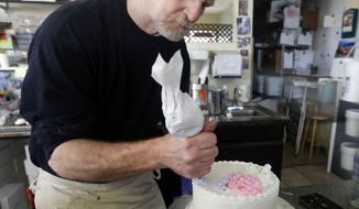FILE - In this March 10, 2014, file photo, Masterpiece Cakeshop owner Jack Phillips decorates a cake inside his store in Lakewood, Colo. The Supreme Court is setting aside a Colorado court ruling against a baker who wouldn’t make a wedding cake for a same-sex couple. But the court is not deciding the big issue in the case, whether a business can refuse to serve gay and lesbian people. (AP Photo/Brennan Linsley, File)