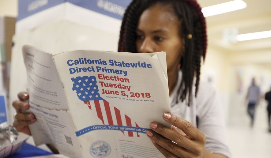 Nikko Johnson reviews the California primary election guide at San Francisco City Hall Tuesday, June 5, 2018. The 40-year-old nurse was waiting for her mother to arrive at the polling station so they could vote together. (AP Photo/Lorin Eleni Gill)