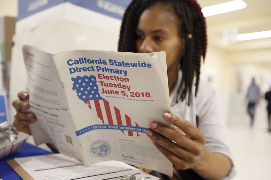 Nikko Johnson reviews the California primary election guide at San Francisco City Hall Tuesday, June 5, 2018. The 40-year-old nurse was waiting for her mother to arrive at the polling station so they could vote together. (AP Photo/Lorin Eleni Gill)