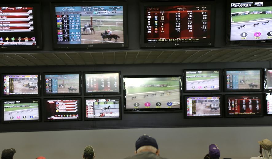 In this May 14, 2018, file photo, men watch horse racing on an array of screens at Monmouth Park Racetrack in Oceanport, N.J. New Jersey lawmakers are facing some key decisions Monday, June 4, as they race to legalize sports betting after winning a case in the U.S. Supreme Court. (AP Photo/Seth Wenig, File)