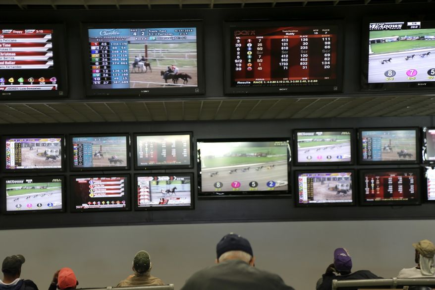 In this May 14, 2018, file photo, men watch horse racing on an array of screens at Monmouth Park Racetrack in Oceanport, N.J. New Jersey lawmakers are facing some key decisions Monday, June 4, as they race to legalize sports betting after winning a case in the U.S. Supreme Court. (AP Photo/Seth Wenig, File)