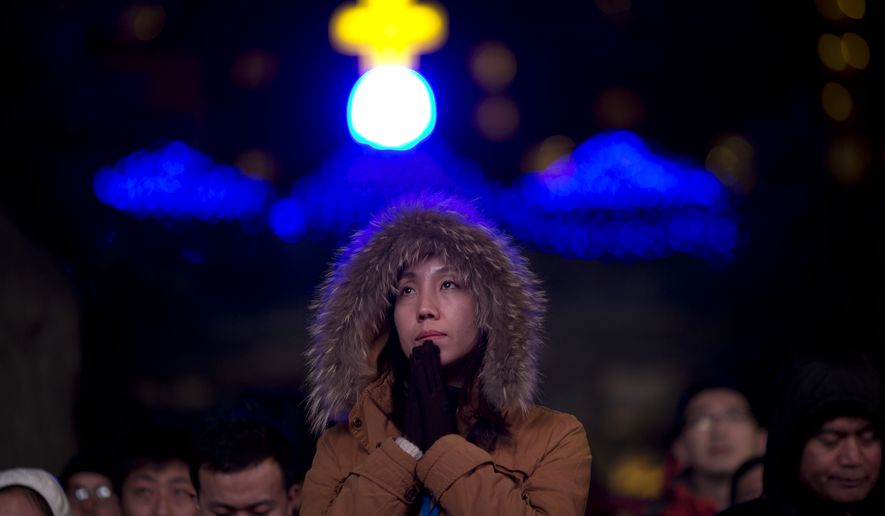 A Chinese woman prays as she takes part in a mass on the eve of Christmas at the South Cathedral official Catholic church in Beijing, China, Wednesday, Dec. 24, 2014. Estimates for the number of Christians in China range from the conservative official figure of 23 million to as many as 100 million by independent scholars, raising the possibility that Christians may rival in size the 85 million members of the ruling Communist Party. (AP Photo/Ng Han Guan)