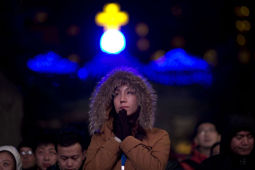 A Chinese woman prays as she takes part in a mass on the eve of Christmas at the South Cathedral official Catholic church in Beijing, China, Wednesday, Dec. 24, 2014. Estimates for the number of Christians in China range from the conservative official figure of 23 million to as many as 100 million by independent scholars, raising the possibility that Christians may rival in size the 85 million members of the ruling Communist Party. (AP Photo/Ng Han Guan)