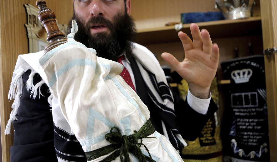 In this Wednesday, May 30, 2018, Rabbi Arie Zeev Raskin, the leader of Cyprus' 3,500-strong Jewish community, holds a rare 110 year-old Torah scroll that comes from Bohemia in what is now the western-most pat of the Czech Republic, at a synagogue inside Cyprus' Jewish Community Center in the town of Larnaca. The scrolls will be put on display in a new museum on the eastern Mediterranean island-nation that its founders envision as a bridge-builder to the Arab world and beyond, a place where visitors who may never set foot in Israel can learn about the Jewish faith, the Holocaust and the tumultuous beginnings of the Jewish state. (AP Photo/Petros Karadjias)