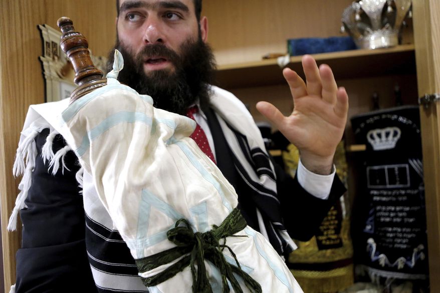 In this Wednesday, May 30, 2018, Rabbi Arie Zeev Raskin, the leader of Cyprus' 3,500-strong Jewish community, holds a rare 110 year-old Torah scroll that comes from Bohemia in what is now the western-most pat of the Czech Republic, at a synagogue inside Cyprus' Jewish Community Center in the town of Larnaca. The scrolls will be put on display in a new museum on the eastern Mediterranean island-nation that its founders envision as a bridge-builder to the Arab world and beyond, a place where visitors who may never set foot in Israel can learn about the Jewish faith, the Holocaust and the tumultuous beginnings of the Jewish state. (AP Photo/Petros Karadjias)