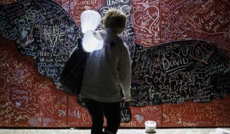Jill Taylor, of Hamilton, Ohio, who lost her father Gary B. Shepherd taking his own life in 2011, steps up to a message board decorated with notes for loved ones during an Out of the Darkness Walk event organized by the Cincinnati Chapter of the American Foundation for Suicide Prevention in Sawyer Point park, Sunday, Oct. 15, 2017, in Cincinnati. Hundreds of supporters gathered to draw attention to and raise funds for the prevention of suicide that ranks as the tenth leading cause of death in the United States overall according to the Centers for Disease Control (CDC). (AP Photo/John Minchillo)