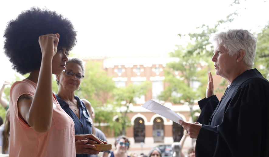 Mariah Parker takes her oath of office for County Commissioner District 2 with her hand on the autobiography of Malcolm X and her mother Mattie Parker by her side on the steps of City Hall in downtown Athens, Ga., Tuesday, June 5, 2018. Parker filled the county commissioner seat vacated by Harry Sims who left his seat to run for mayor. She won the election for District 2 by 13 votes. (Joshua L. Jones/Athens Banner-Herald via AP)