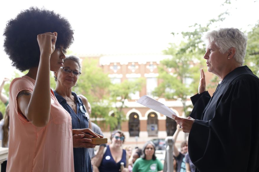 Mariah Parker takes her oath of office for County Commissioner District 2 with her hand on the autobiography of Malcolm X and her mother Mattie Parker by her side on the steps of City Hall in downtown Athens, Ga., Tuesday, June 5, 2018. Parker filled the county commissioner seat vacated by Harry Sims who left his seat to run for mayor. She won the election for District 2 by 13 votes. (Joshua L. Jones/Athens Banner-Herald via AP)