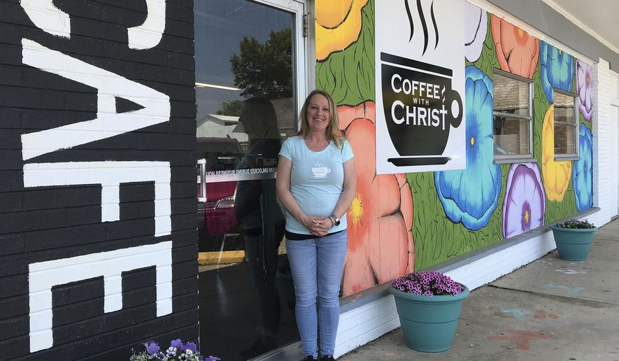 In this May 23, 2018 photo, Melissa Schwalenberg poses outside Coffee with Christ, her new cafe and meeting place in Belleville, Ill. After nearly 20 years of teaching elementary school in the metro-east, Schwalenberg is taking a long coffee break to give back to local kids and adults in a different way. Not far from the cash register, there's a colorful wall of sticky notes where patrons can promote kindness. Each handwritten note offers a free oatmeal, free yogurt, free drink or meal credit to a person in need of a pick-me-up, or someone who might not have enough money to pay their bill. (Cara Anthony /Belleville News-Democrat, via AP)