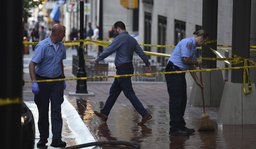 Baltimore City firefighters clean the sidewalk on Light Street following a shooting Friday, June 8, 2018 in Baltimore. Police are looking for a person who shot a woman in the face on a downtown sidewalk and then ran away.The shooting happened early Friday on Light Street. Police said the woman was approached by a person who pulled out a gun and shot her. The person then fled on foot. (Jerry Jackson/The Baltimore Sun via AP)