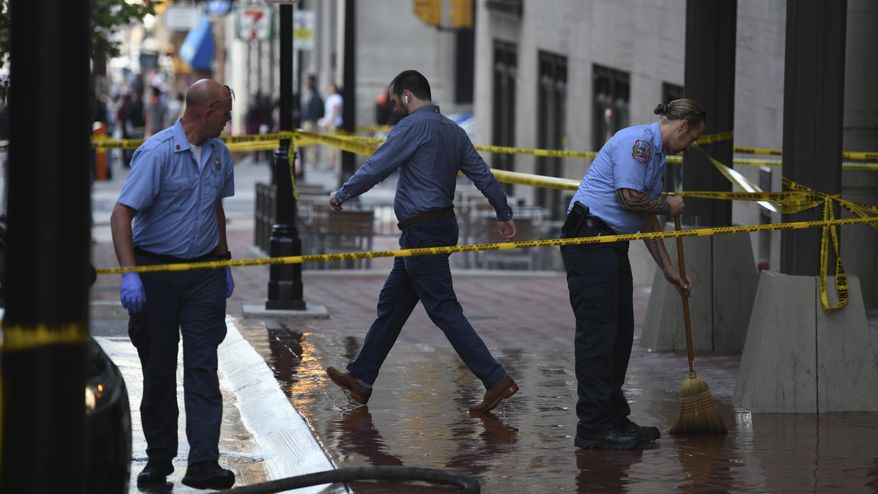 Baltimore City firefighters clean the sidewalk on Light Street following a shooting Friday, June 8, 2018 in Baltimore. Police are looking for a person who shot a woman in the face on a downtown sidewalk and then ran away.The shooting happened early Friday on Light Street. Police said the woman was approached by a person who pulled out a gun and shot her. The person then fled on foot. (Jerry Jackson/The Baltimore Sun via AP)