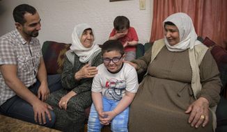 In a Thursday May 31, 2018 photo, Ali Turki Ali, far left, laughs as his step-mother Faiza, second from left, and his mother, Amina, right, watch their grandsons be silly at their new home in Eugene, Ore. The women arrived recently from Turkey where they had been staying since fleeing the war in Syria in 2014. (Andy Nelson/The Register-Guard via AP)