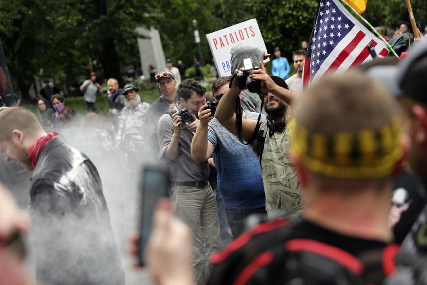 In this June 3, 2018, file photo, photographers capture dueling demonstrations between antifacists known as antifa and a right-wing group called Patriot Prayer in downtown Portland, Ore. (Mark Graves/The Oregonian via AP, file)