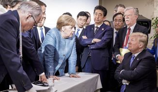In this photo made available by the German Federal Government, German Chancellor Angela Merkel, center, speaks with U.S. President Donald Trump, seated at right, during the G7 Leaders Summit in La Malbaie, Quebec, Canada, on Saturday, June 9, 2018. (Jesco Denzel/German Federal Government via AP)