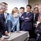 In this photo made available by the German Federal Government, German Chancellor Angela Merkel, center, speaks with U.S. President Donald Trump, seated at right, during the G7 Leaders Summit in La Malbaie, Quebec, Canada, on Saturday, June 9, 2018. (Jesco Denzel/German Federal Government via AP)