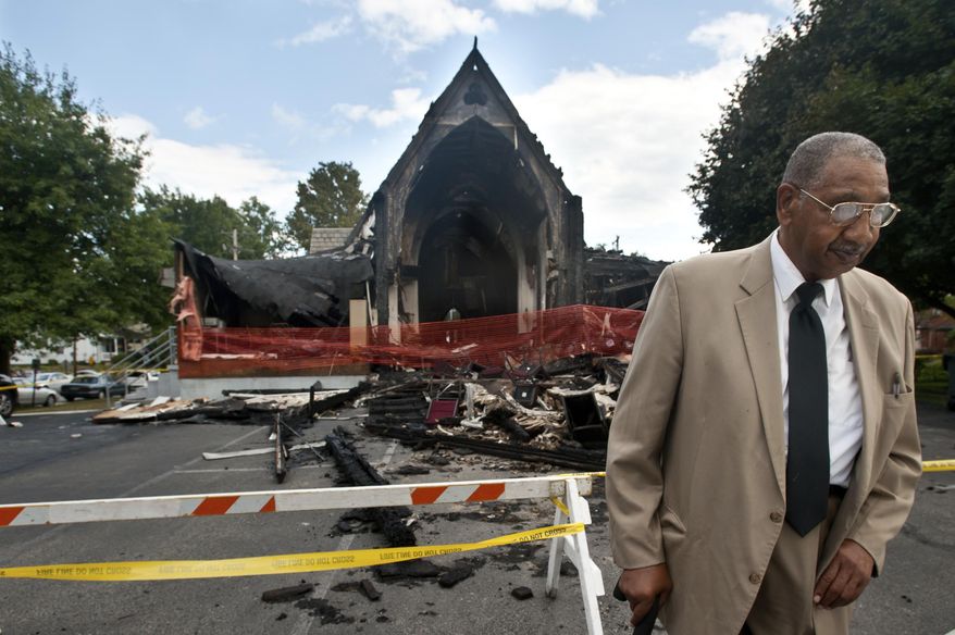 In this Sunday, Sept. 21, 2014 photo, James McGee, 86, of Tarentum, stands beyond the yellow police tape that surrounds the burnt remains of St. Paul Baptist Church on Second Street in Oakmont, Pa. McGee, who has been attending the church since 1992 and is the Chairman of the Deacon Board for the church, came with grandchildren in tow to the church's Sunday service, held instead across the street at Riverview Community Action Corp. St. Paul Baptist Church was rebuilt and had it's first service June 3, 2018. (Stephanie Strasburg/Pittsburgh Tribune-Review via AP)