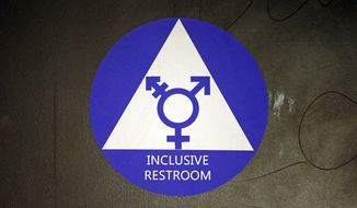 In this May 17, 2016, file photo, a new sticker designates a gender neutral bathroom at Nathan Hale high school in Seattle. (AP Photo/Elaine Thompson, File)