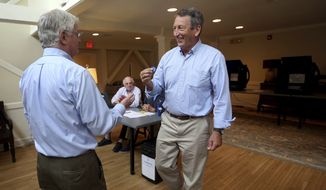 Poll volunteer Tom Spain hands out stickers to former Gov, Mark Sanford after he cast his own ballot at Alhambra Hall polling station Tuesday, June 12, 2018, in Mt. Pleasant, S.C. (Grace Beahm Alford/The Post And Courier via AP) ** FILE **