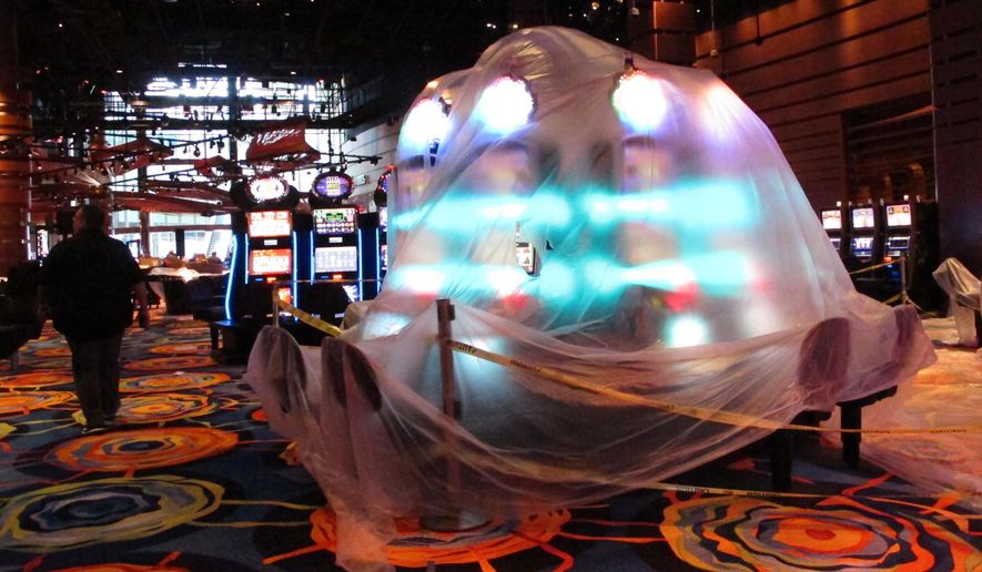 This June 12, 2018 photo shows a bank of illuminated slot machines under plastic wrap inside the Ocean Resort Casino as the former Revel property prepares to reopen under a new owner and a new brand on June 28. (AP Photo/Wayne Parry)