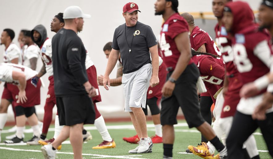 Washington Redskins head coach Jay Gruden, center, smiles during an NFL football team practice, Wednesday, June 13, 2018, in Ashburn, Va. (AP Photo/Nick Wass)