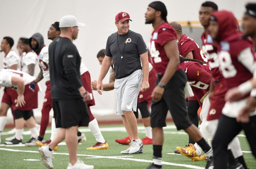 Washington Redskins head coach Jay Gruden, center, smiles during an NFL football team practice, Wednesday, June 13, 2018, in Ashburn, Va. (AP Photo/Nick Wass)