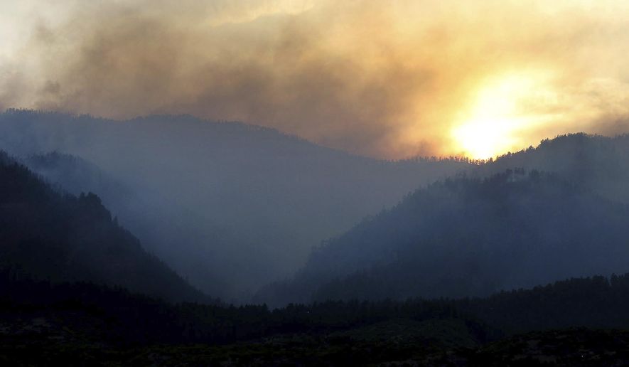 As the sun sets, smoke rises from a 416 Fire burn area west of the Falls creek Ranch subdivision late Wednesday, June 13, 2018, near Durango, Colo. (Jerry McBride/The Durango Herald via AP)