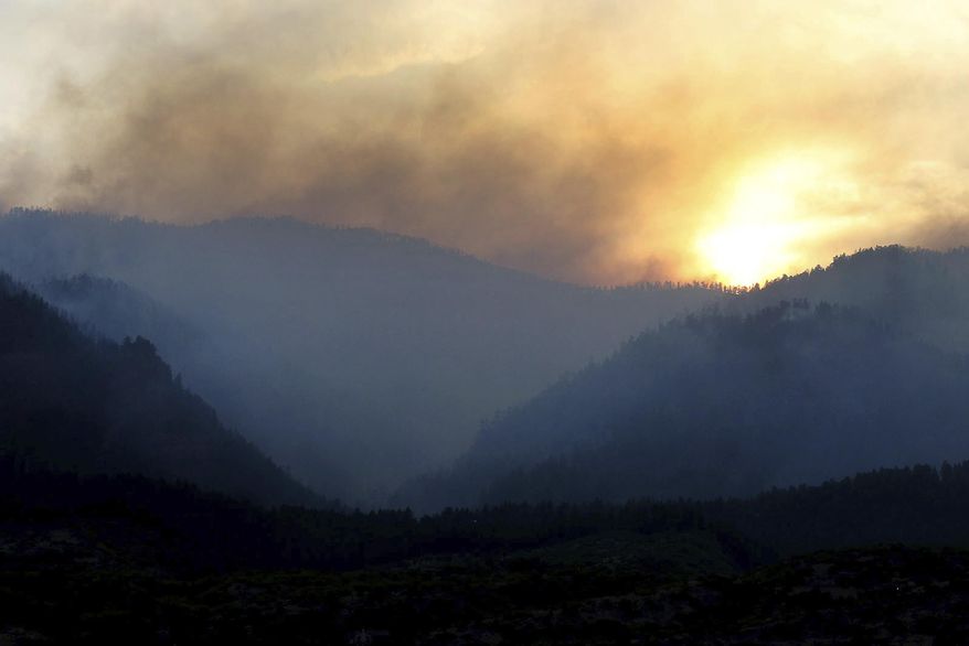 As the sun sets, smoke rises from a 416 Fire burn area west of the Falls creek Ranch subdivision late Wednesday, June 13, 2018, near Durango, Colo. (Jerry McBride/The Durango Herald via AP)