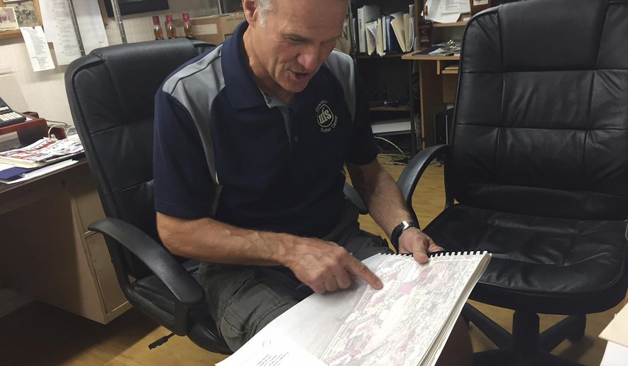 In this June 5, 2018 photo, Pierre Serafin, owner of UFS Downtown Outlet Center, and  secretary-treasurer of the South Side Business Club looks at the 2002 Heart of Peoria Plan in his office in Peoria, Ill. After almost 90 years, the South Side Business Club will end in bittersweet irony. The club, formed to bolster commercial and community interests in what once was the core of the city, will disband to make one final contribution to Peoria. In shutting down. (Phil Luciano/Journal Star via AP)
