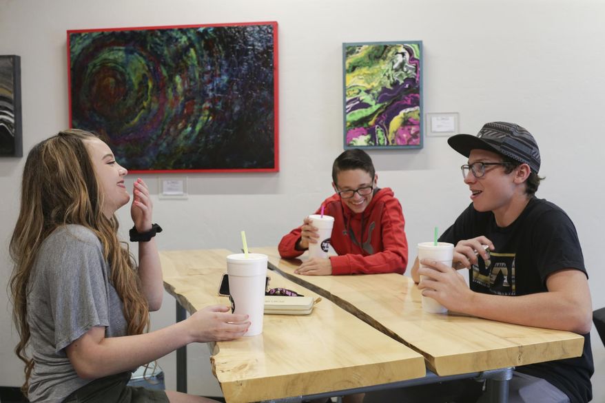 In a June 7, 2018 photo, Laurna Chapman, Landon Pinnock, with hat, and JR Chapman have sodas at The Drink Factory in Idaho Falls, Idaho. Soda shops, also known as soda shacks, have become a mainstay in the region. (John Roark/The Idaho Post-Register via AP)