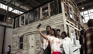 FILE - In this April 1, 2018 file photo, Cheryl Galloway, of Providence, R.I., uses a mobile phone to take a photo with family members in front of the rebuilt house of Rosa Parks at the WaterFire Arts Center in Providence, R.I. The house where Parks sought refuge in Detroit after fleeing the South will be auctioned after being turned into a work of art. Guernsey&#39;s auction house says the sale will be held mid-summer and that it&#39;s expected to fetch seven figures. (AP Photo/Steven Senne, File)