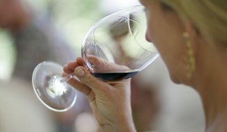 A woman evaluates the aroma of a wine in California on June 7, 2008. (Associated Press) **FILE**