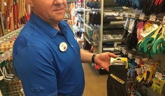 In this Thursday, June 14, 2018 photo, Mark Driscoll, owner of the Ace Hardware in Sugar Grove, Ill., holds a pair of gloves like the type he tried on recently and discovered a man&#39;s ring in one of the fingers. He&#39;s now trying to find the owner of the ring but so far has had no luck. (Denise Crosby/Chicago Tribune via AP)
