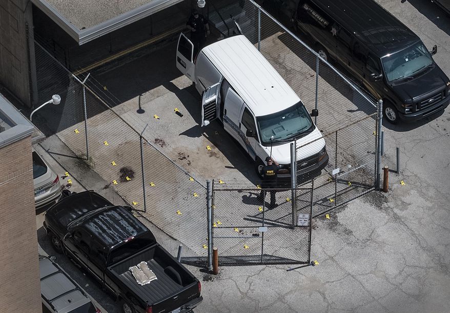 Evidence markers dot the pavement just outside the Wyandotte County courthouse, Friday, June 16, 2018, in Kansas City, Kan. Authorities say one sheriff's deputy is dead and another is critically wounded after they were overcome by an inmate while driving a transport vehicle near the courthouse. (The Kansas City Star via AP)