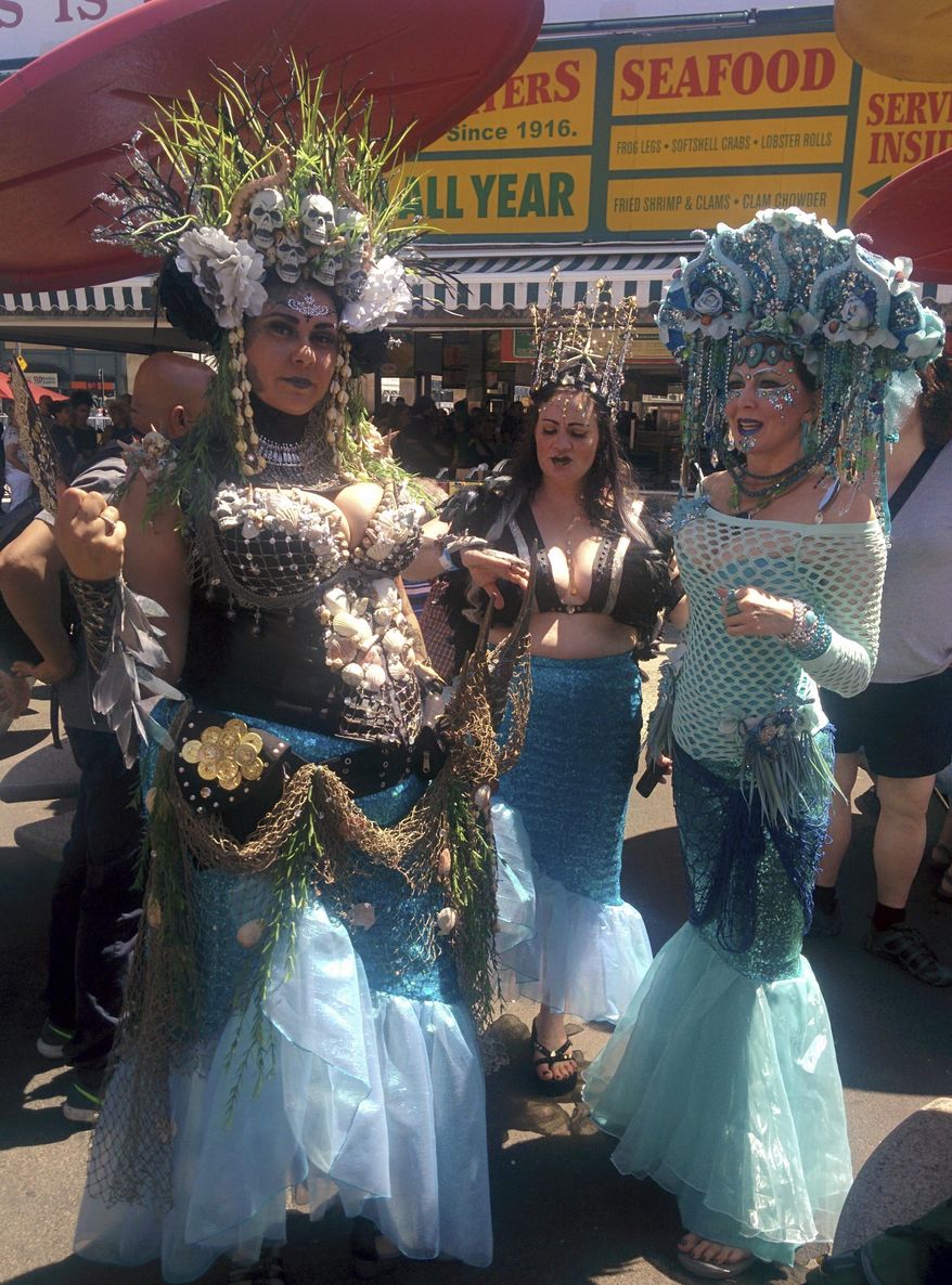 Baltimore's Charm City Tails members Lisa Locklear, left, Kristen Edwards, center, and Rae Beth pose for a photo at New York's Coney Island before the 36th annual Mermaid Parade, Saturday, June 16, 2018. (AP Photo/Julie Walker)