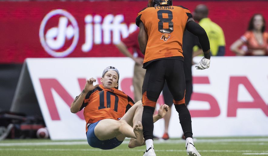 B.C. Lions' Marcell Young (8) knocks down a spectator that ran onto the field of play during the first half of a CFL football game against the Montreal Alouettes in Vancouver, British Columbia, Saturday June 16, 2018. (Darryl Dyck/The Canadian Press via AP)