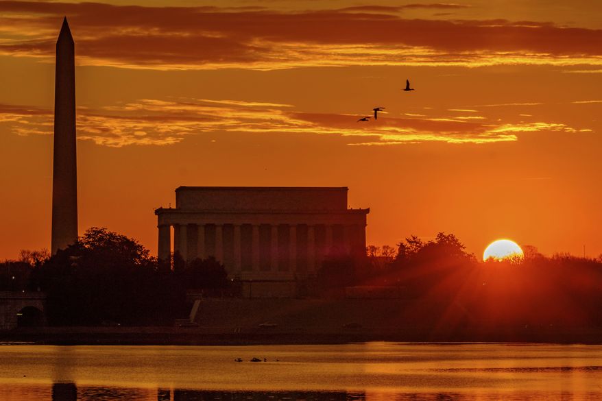 In this Tuesday, March 6, 2018, photo, the sun peaks over the horizon next to the Washington Monument and Lincoln Memorial at daybreak along the Potomac River in Washington. (AP Photo/J. David Ake) **FILE**